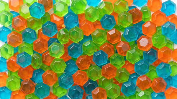 Flat lay of QUOR Enhance gummies in green, blue, and orange